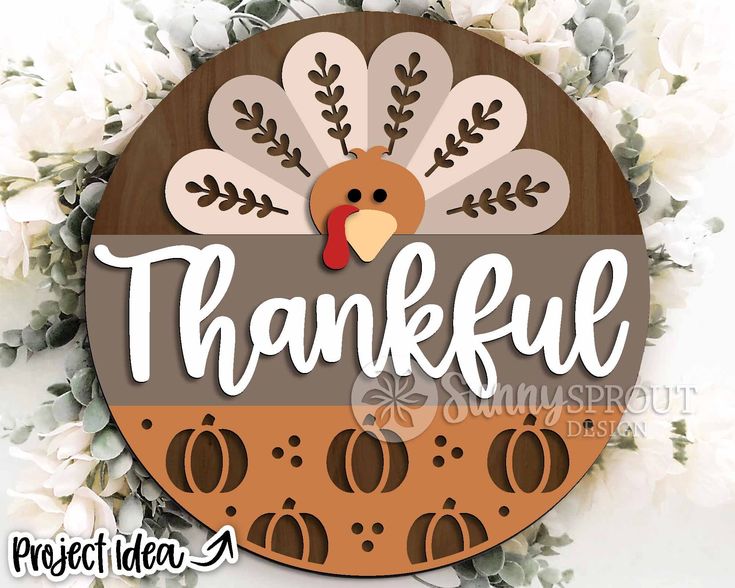 a wooden sign that says,'grateful'with a turkey on it and flowers in the background