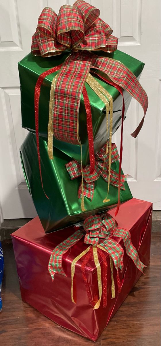 three wrapped presents stacked on top of each other in front of a door with ribbons