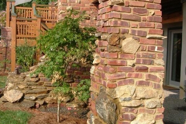 a brick building with a small tree growing out of it's side wall in front of a house