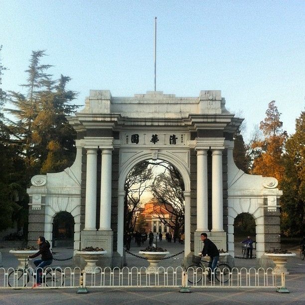 people are sitting on benches in front of an arch