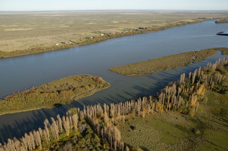 an aerial view of the water and land in this country side area with trees on both sides