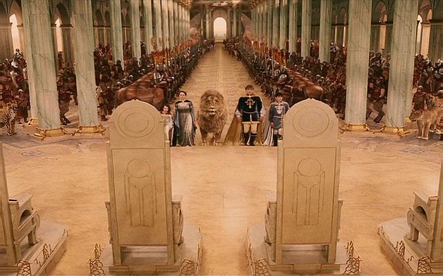 two men standing in front of an elaborately decorated hall with lions and other statues