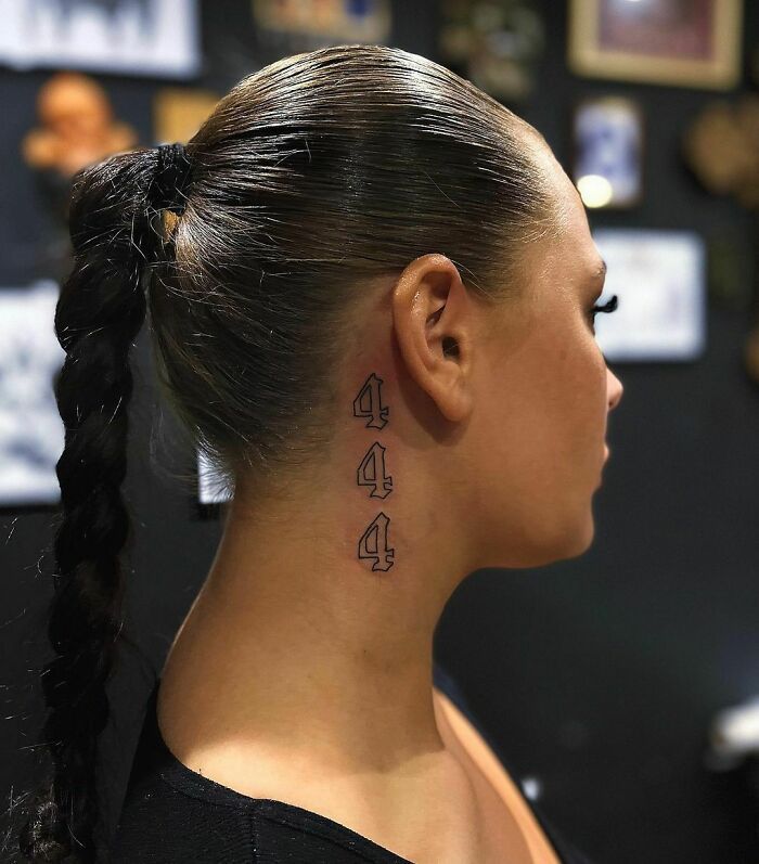 a woman with her hair in a ponytail has a tattoo on her left side of her neck