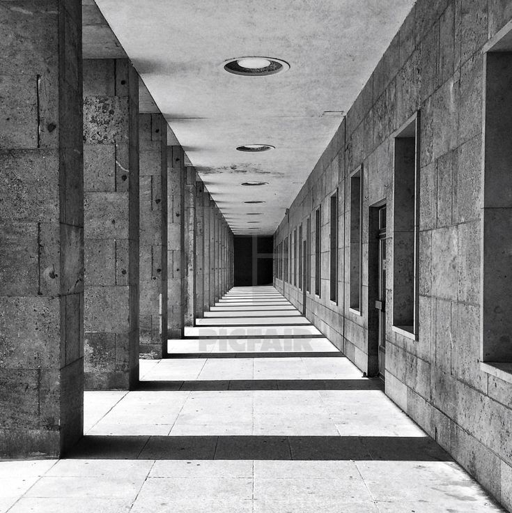 an empty hallway with several windows and doors on both sides, in black and white