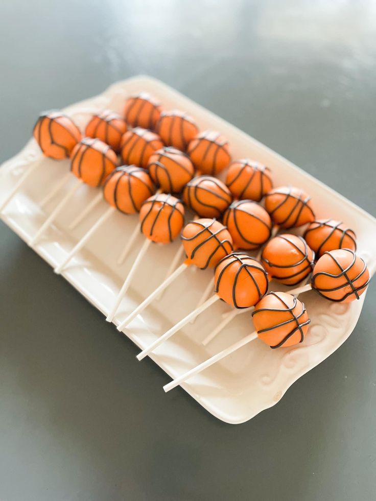 several orange basketballs sitting on top of a white plate with toothpicks in them