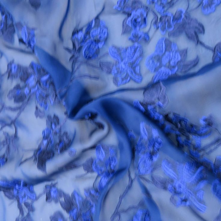 a blue fabric with flowers on it is shown in close up mode, as well as blurry background