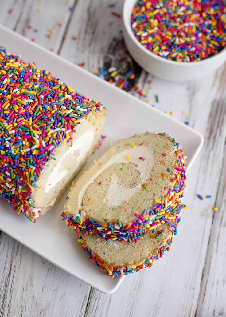 a white plate topped with a cake covered in sprinkles and frosting