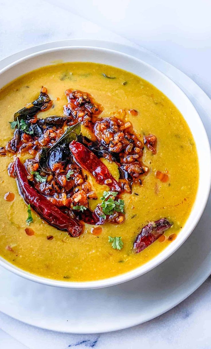 a white bowl filled with yellow soup and garnished with toppings on top