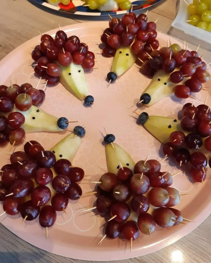 grapes and pears are arranged in the shape of hedgehogs on a plate