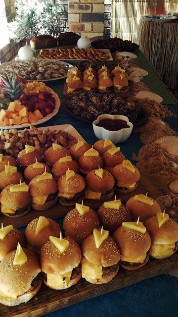 a table topped with lots of different types of food on buns covered in cheese