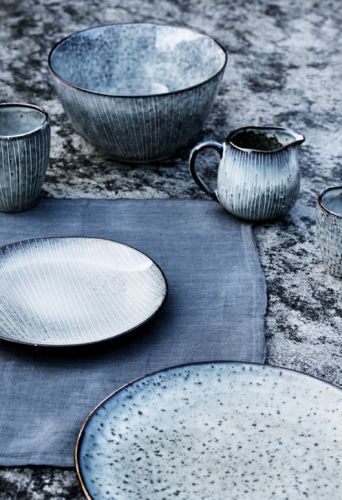 a blue place mat with dishes and cups on it, sitting next to each other