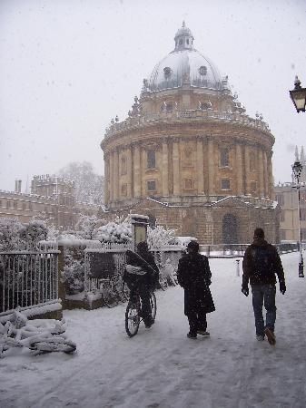 two people walking in the snow near a building