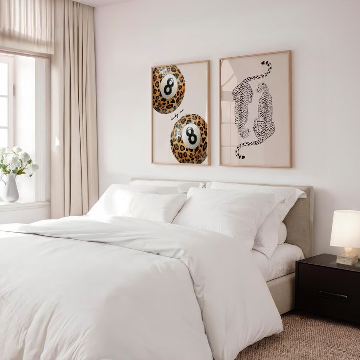 a bed with white sheets and pillows in a bedroom next to two pictures on the wall