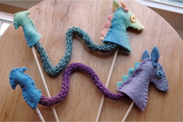 four knitted horses on sticks sitting on top of a wooden table