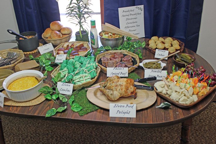 an assortment of food is displayed on a table with blue drapes in the background