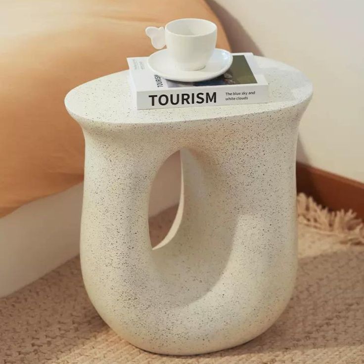 a white table with a book on it and a cup sitting on top of it