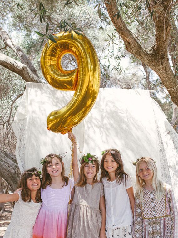 four girls holding up a number balloon in the air