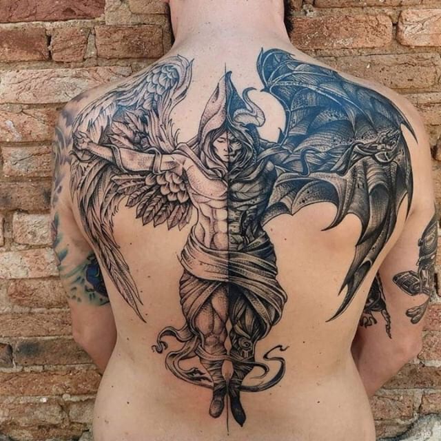 a man with tattoos on his back is standing in front of a brick wall and has an angel tattoo on his back