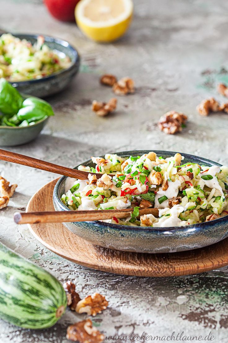 a bowl filled with coleslaw and nuts next to other bowls full of vegetables