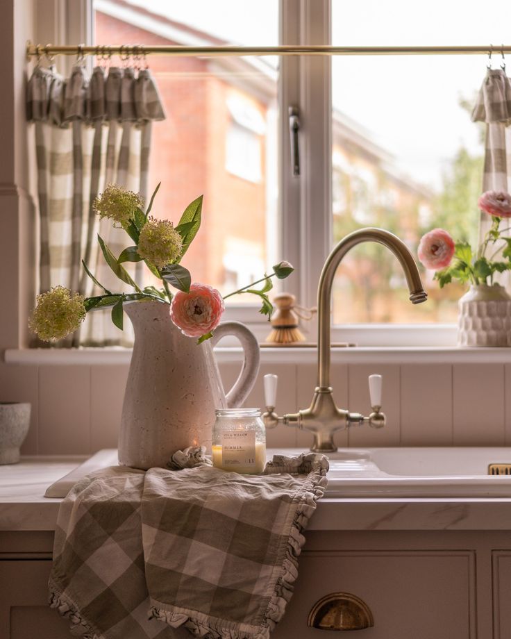 a kitchen sink with flowers in a vase on the counter next to it and a window