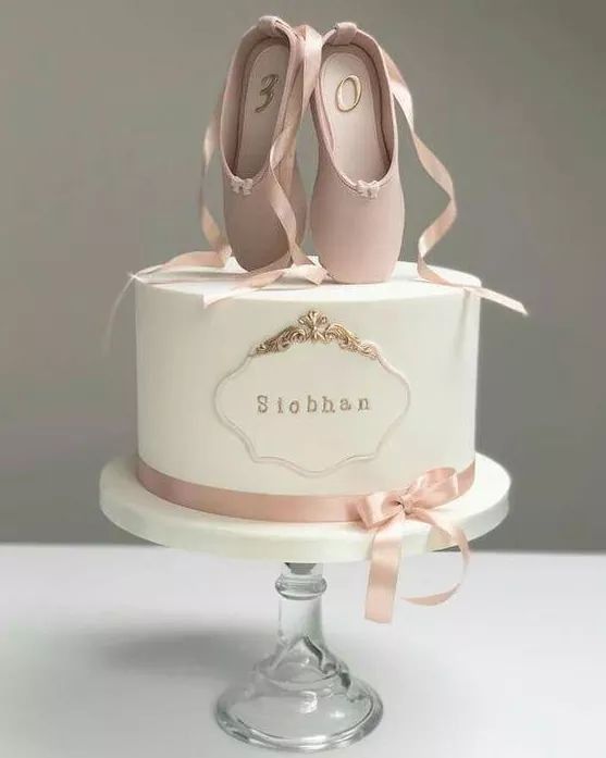 a white cake with pink ballet shoes on top