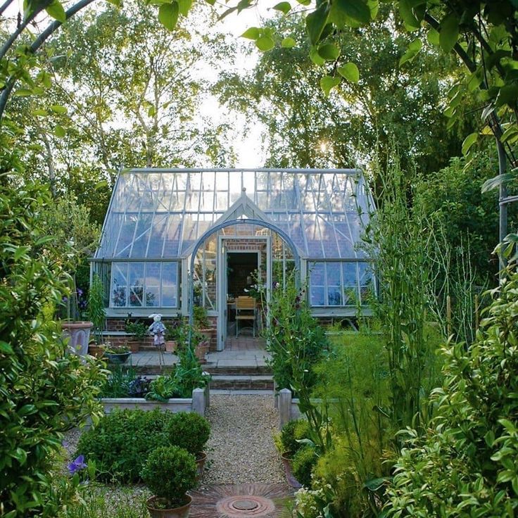 a house that is surrounded by trees and plants in the middle of a garden area