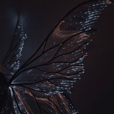 a large butterfly flying through the air with lights on it's wings and body