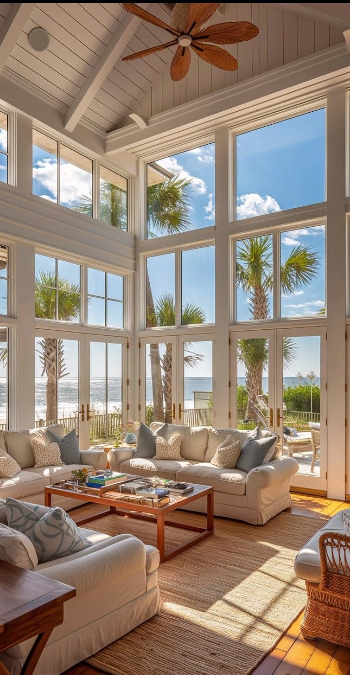 a living room filled with lots of furniture and large windows overlooking the ocean on a sunny day