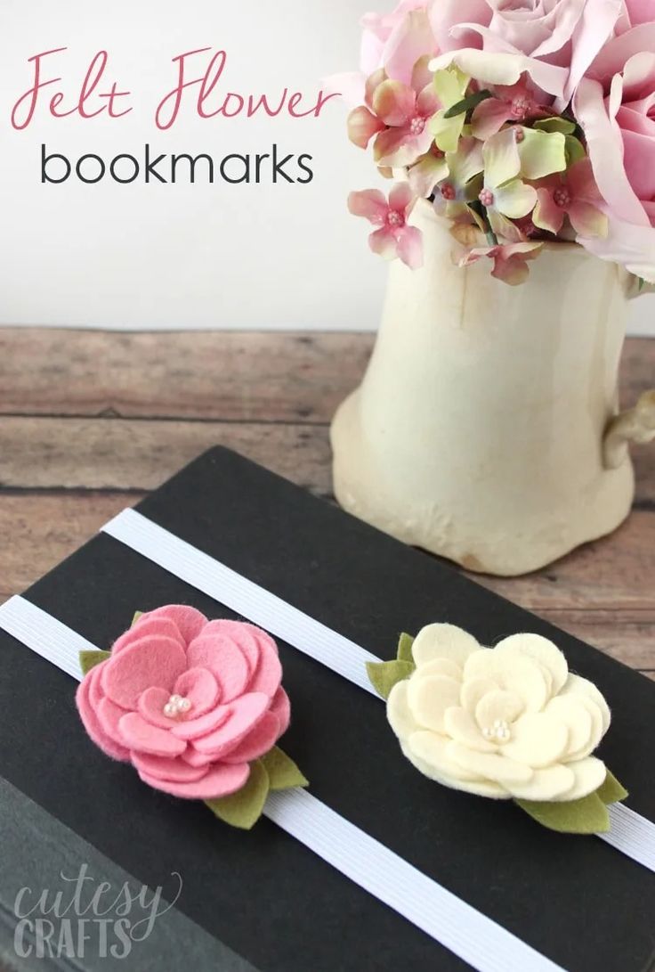 two flowers are sitting on top of a black and white striped box with the words felt flower bookmarks