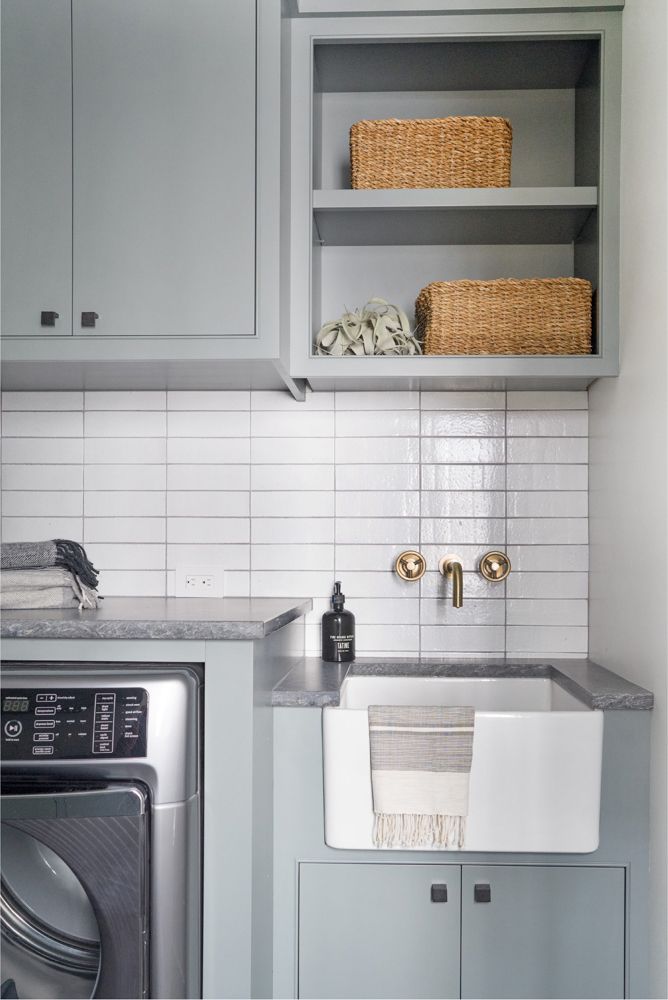 a washer and dryer in a small room with gray cabinets, white tile