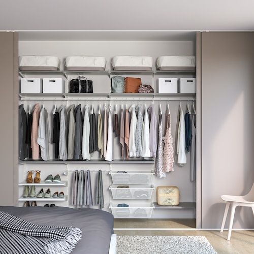 an organized closet with clothes, shoes and other items on shelves next to a bed