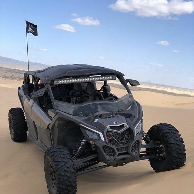 a can - am commander off road vehicle driving in the sand with a flag on top