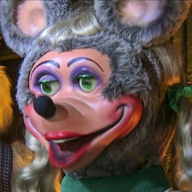 a close up of a person wearing a mouse mask with long blonde hair and green eyes