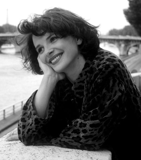 a black and white photo of a woman leaning on a wall with her hand under her chin