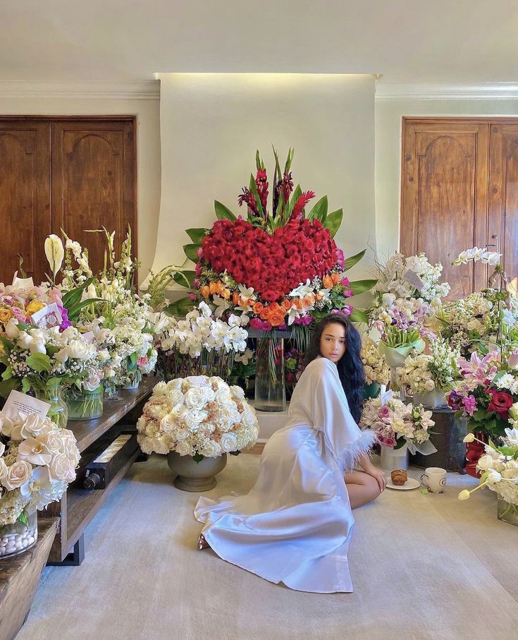 a woman sitting on the floor surrounded by flowers