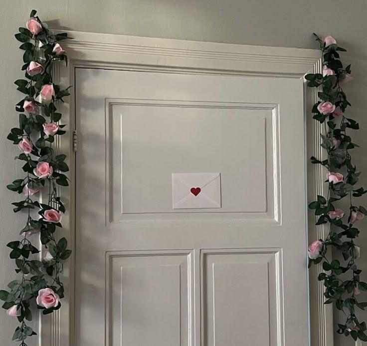 a white door decorated with pink roses and an envelope that says love written on it