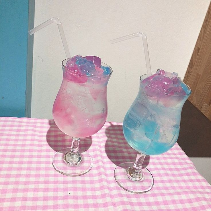 two glasses filled with liquid sitting on top of a pink and white checkered table cloth