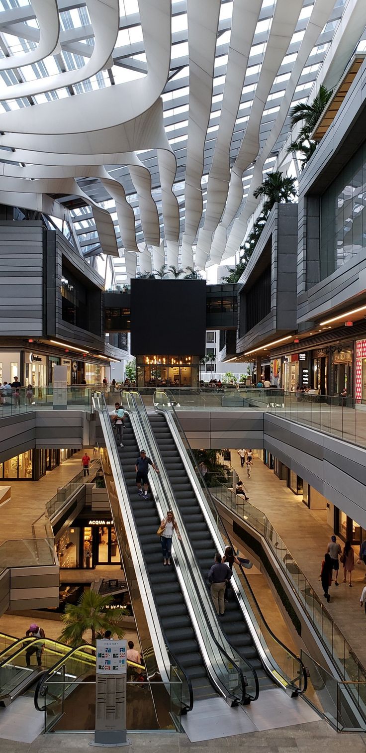 an escalator in a shopping mall with people on the other side and two escalators