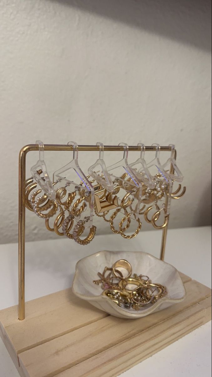 a wooden stand with some gold jewelry on it and a white bowl in the middle