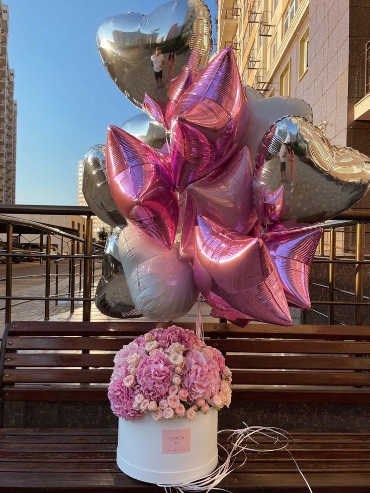 a bunch of balloons that are sitting on a bench with some flowers in the middle