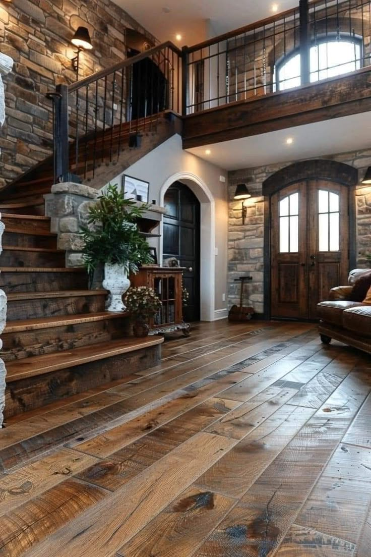 a living room filled with lots of furniture and stone walls next to a stair case