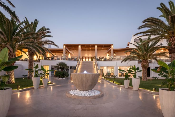 a large fountain in the middle of a courtyard with palm trees and lights around it