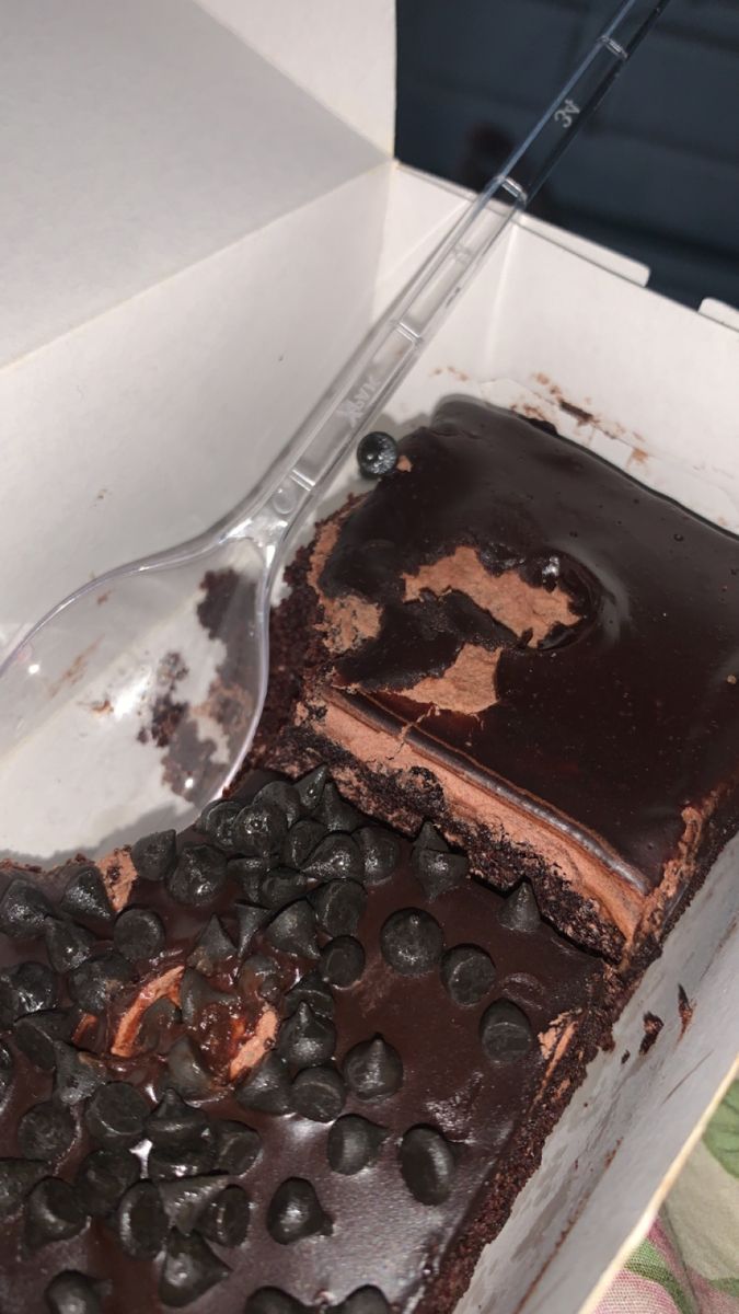 a cake in a box with chocolate chips on the side and a spoon sticking out of it