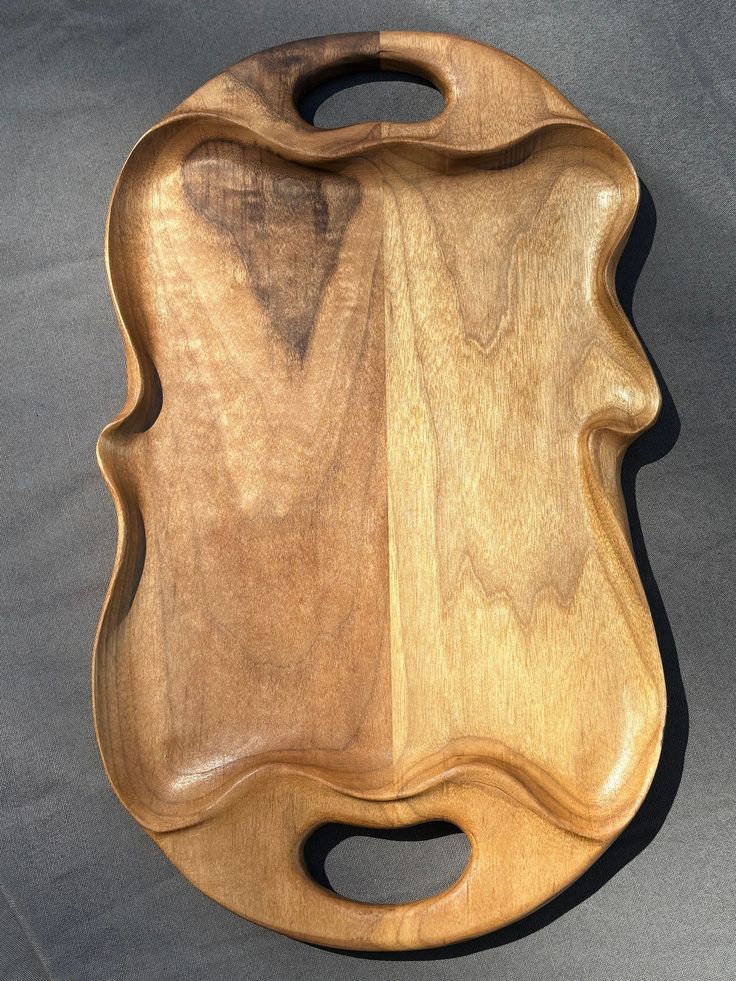 a wooden cutting board sitting on top of a gray table next to a knife holder