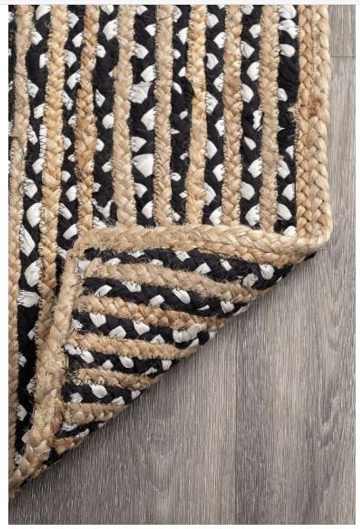 black and white rug with braided edges on wooden floor, closeup view from above