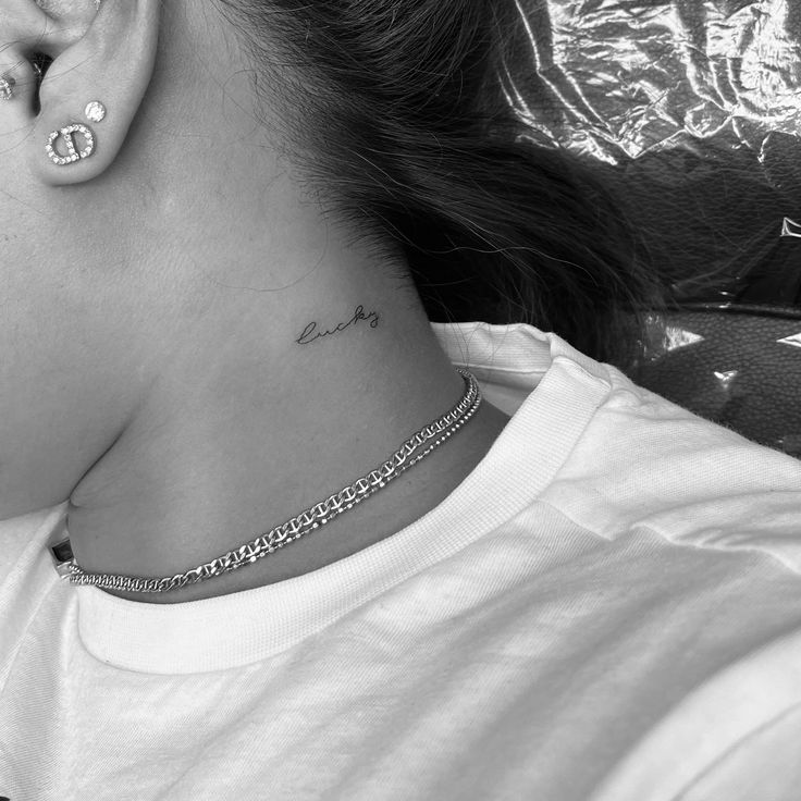 a woman with a tattoo on her neck wearing a pair of ear piercings in front of her head