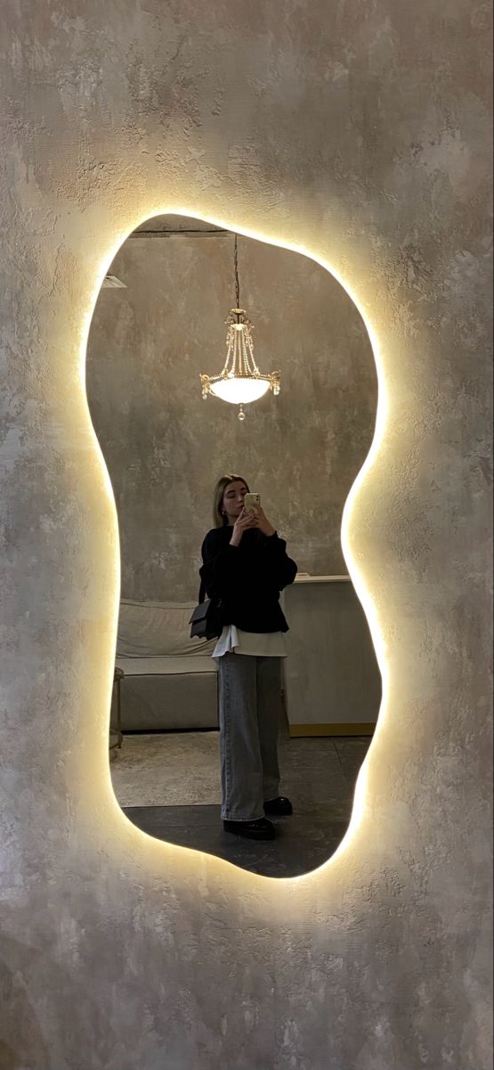 a woman taking a selfie in front of a mirror with a light hanging from the ceiling