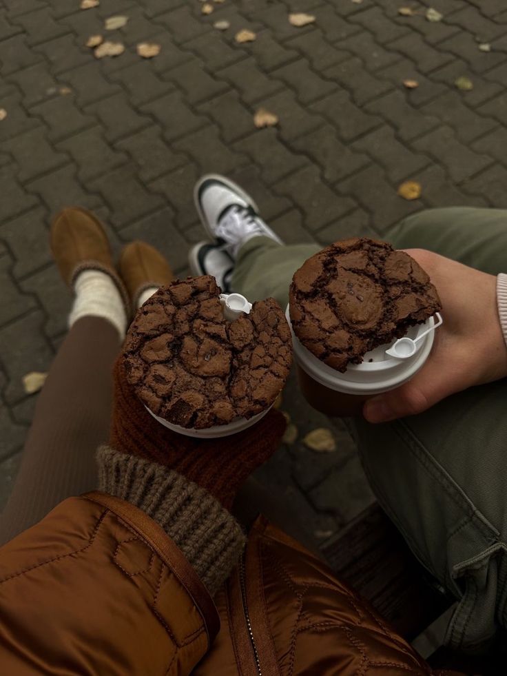 two people sitting on the ground holding cups with food in them