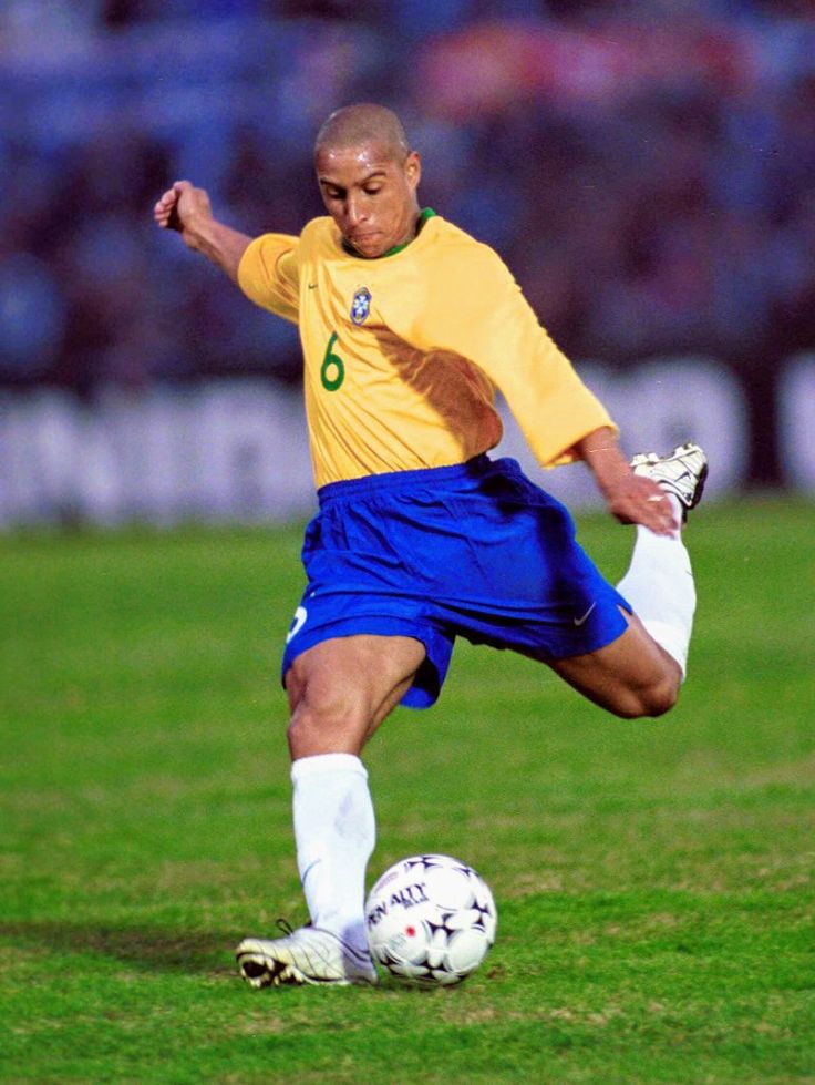 a man kicking a soccer ball on top of a field