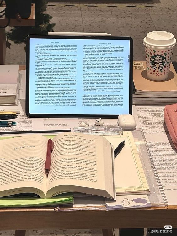 an open laptop computer sitting on top of a table next to books and a cup of coffee